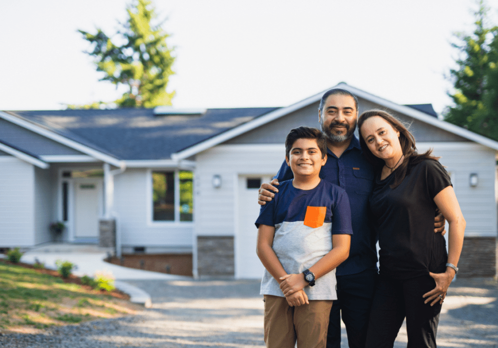 A small, happy family in front of their home.