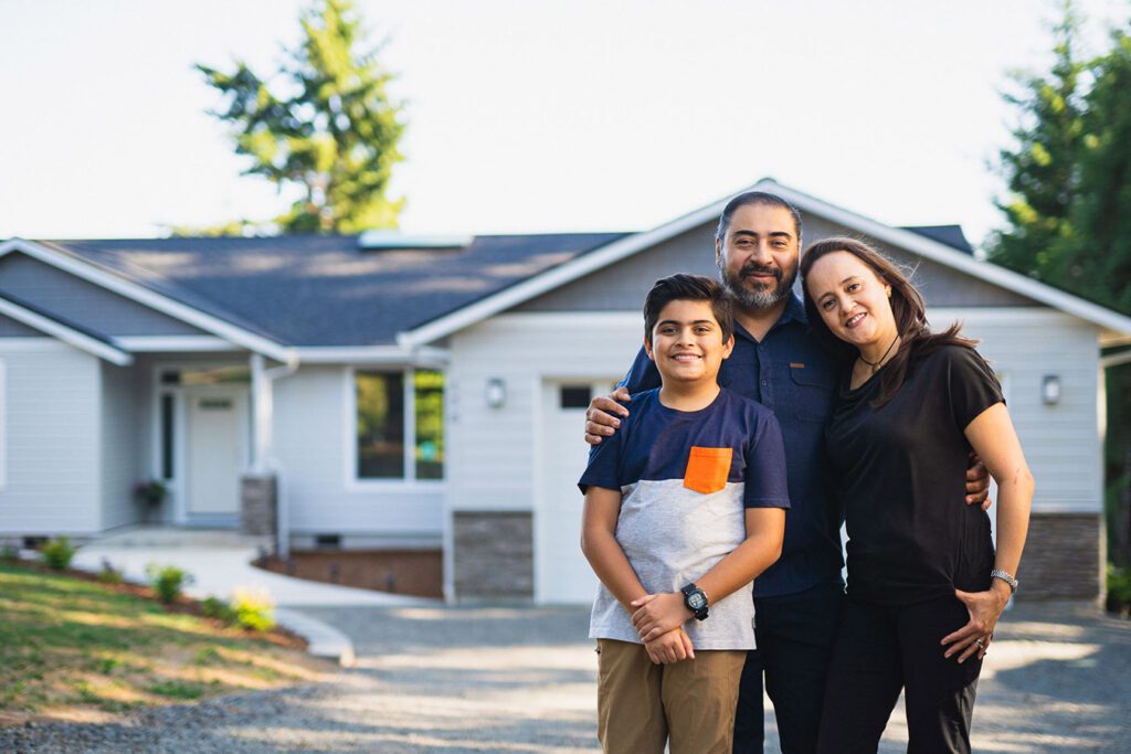A happy family standing outside their new home.