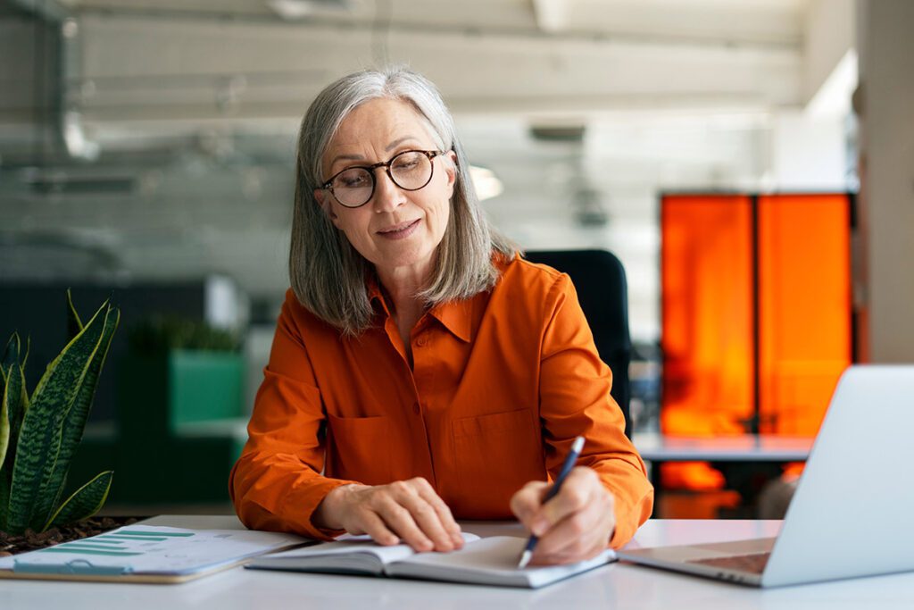 A mature woman writing in her notebook.