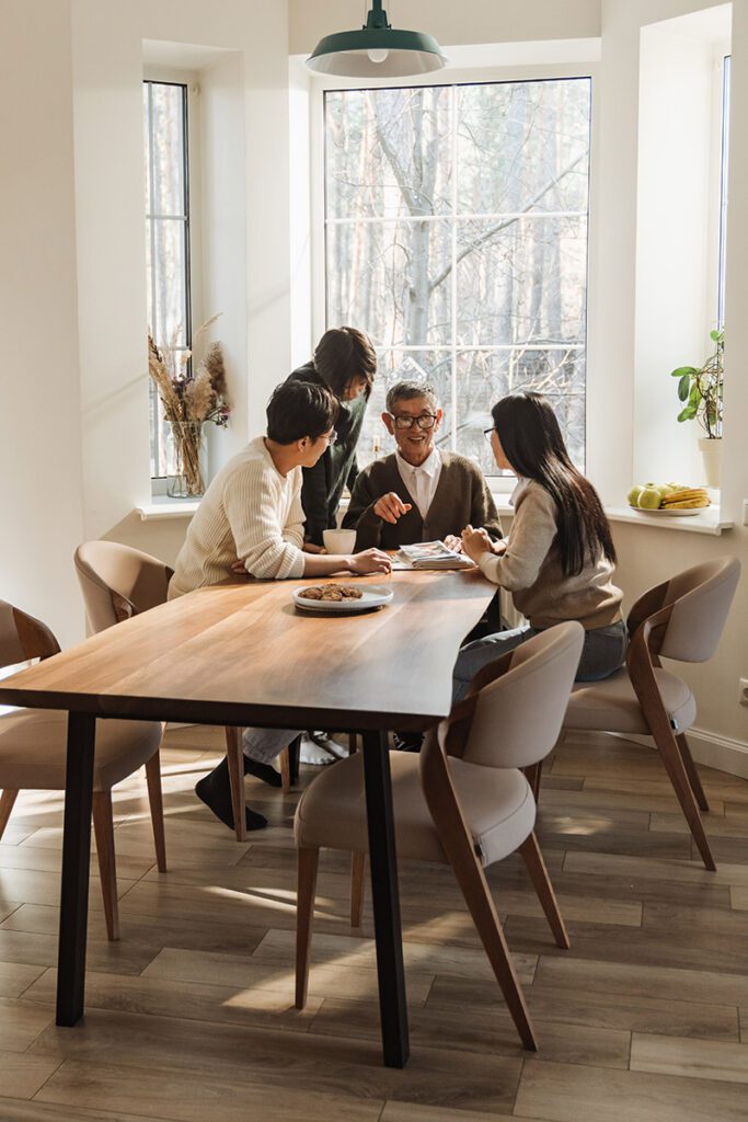 Multigenerational family sitting together at a modern dining table.