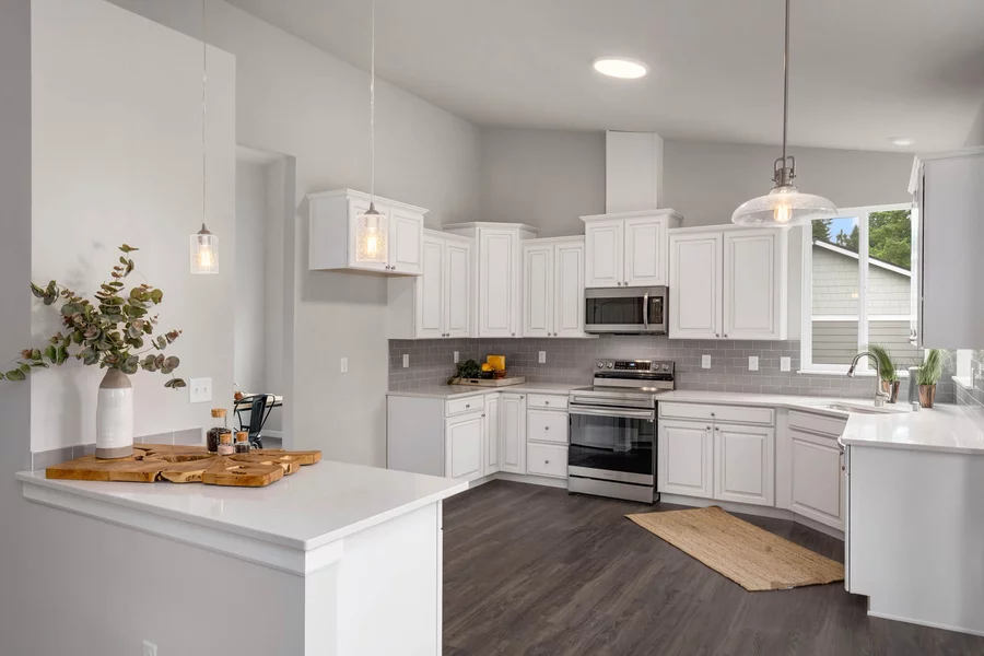 Modern white kitchen with quartz counters, a gray subway tile backsplash and stainless appliances.